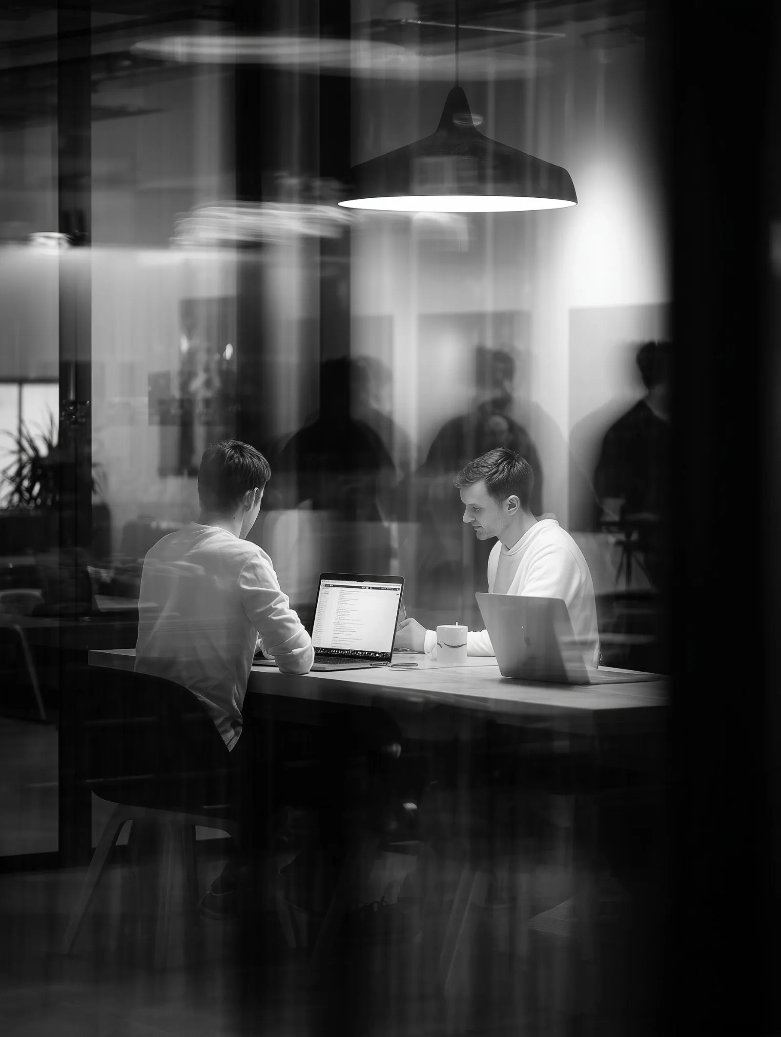 Two professionals working on laptops in a modern office
